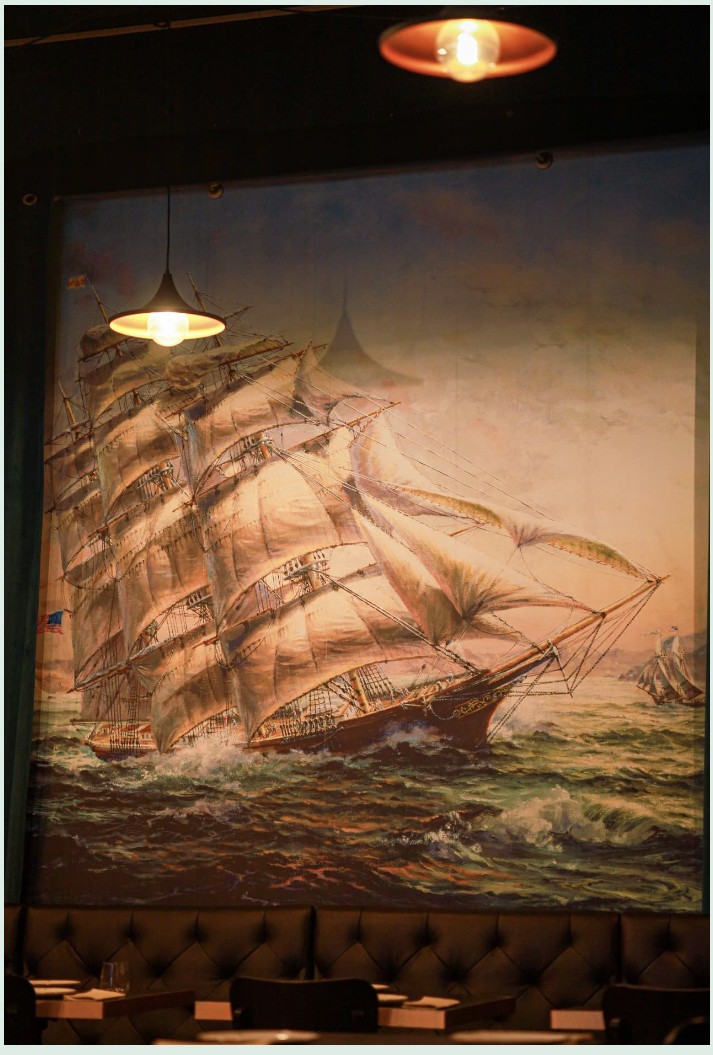 Large Atlantic sailing-ship artwork above the banquette seating inside Enora restaurant in Lisbon