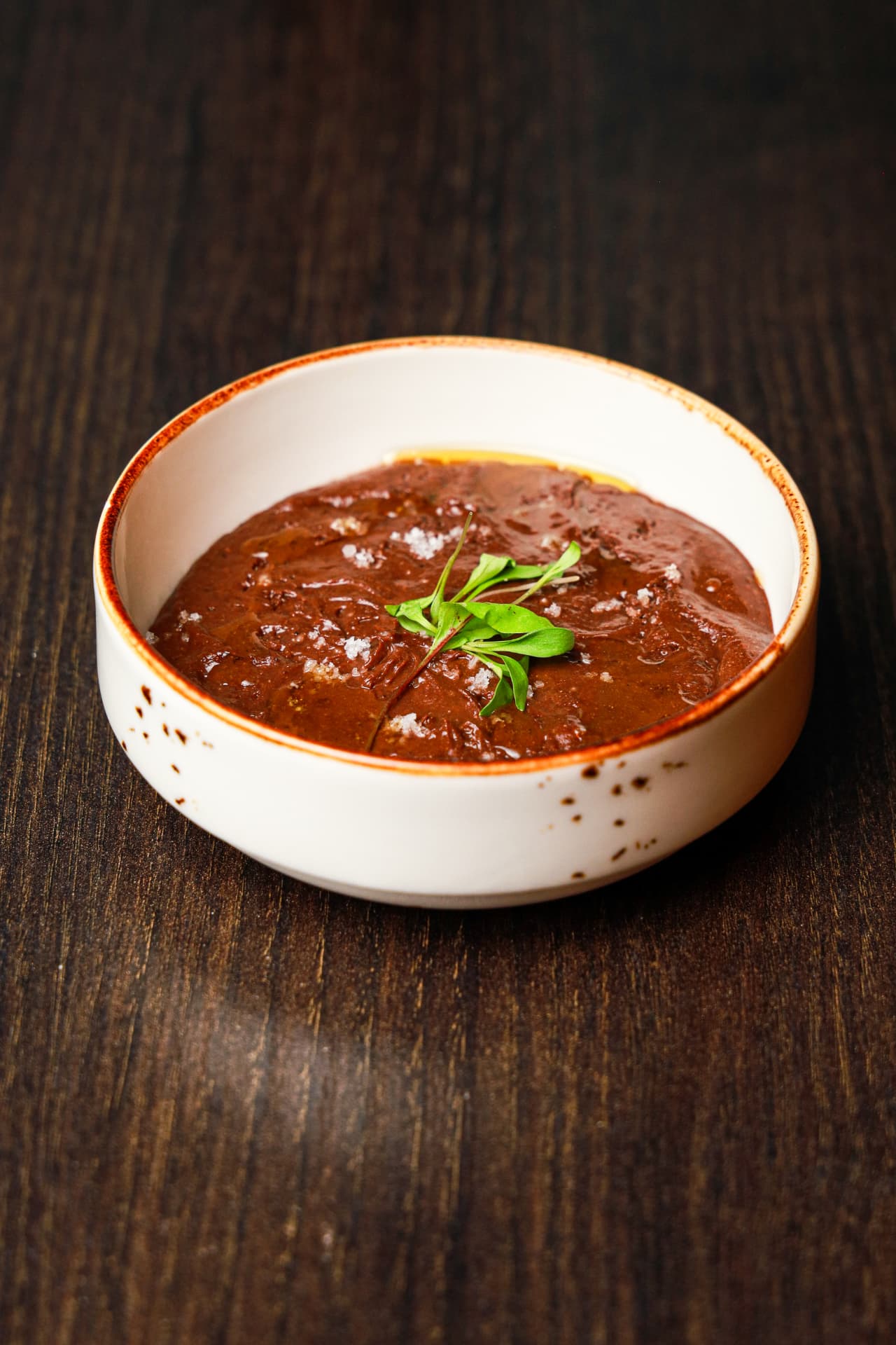 Chocolate mousse topped with sea salt and fresh herbs, served in a white bowl at Enora