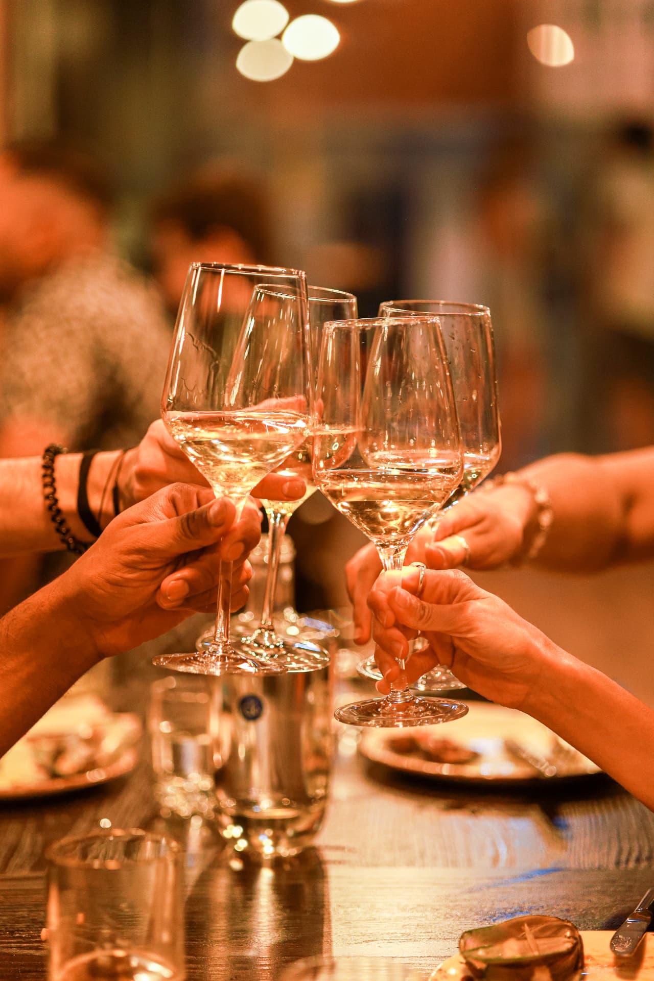 Guests raising wine glasses over dinner at Enora
